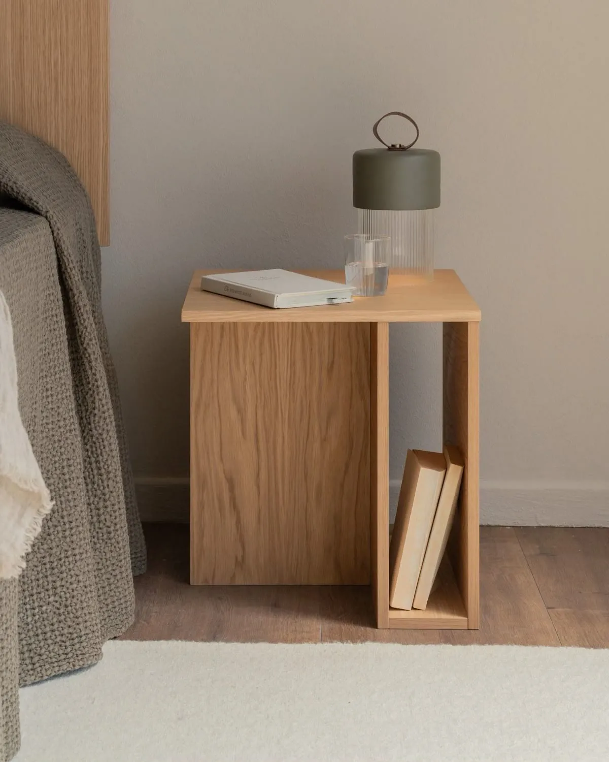 Mesa de luz de roble con un nicho lateral para libros, al lado de la cama